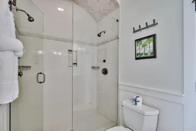 a white bathroom with a shower and a toilet at Sylvia's Cottage in Rosemary Beach