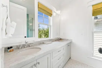 a white bathroom with a sink and a window at Beach Bear Cottage in Watersound Beach
