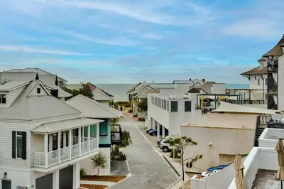 a city street with houses and the ocean in the background at Savannah 1E in Rosemary Beach