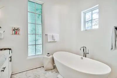 a white bathroom with a tub and a window at Harper Cottage & Carriage House in Rosemary Beach