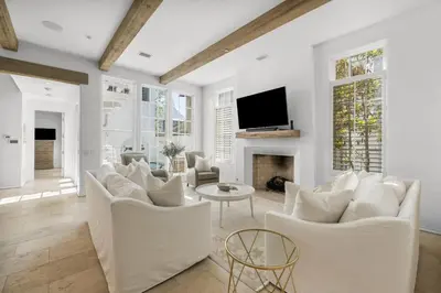 a living room with white furniture and a flat screen tv at Harper Cottage & Carriage House in Rosemary Beach