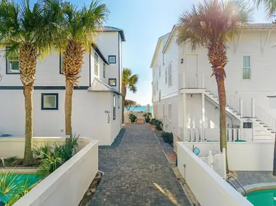 a pathway between two buildings with palm trees at Wilder Dreams in Seacrest