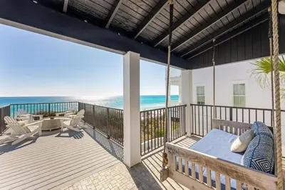 a porch with a swing and the ocean at Wilder Dreams in Seacrest