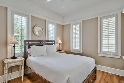 a bedroom with a large white bed and windows at Lola's Carriage House in Rosemary Beach