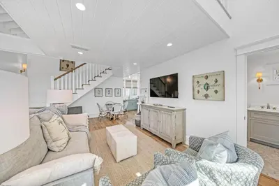 a living room with a couch and a tv at Deauville Carriage House in Rosemary Beach
