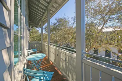 a porch with two chairs and a table at Deauville Carriage House in Rosemary Beach