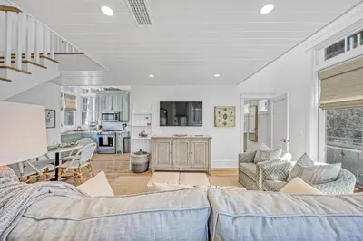 a living room with a couch and a kitchen at Deauville Carriage House in Rosemary Beach
