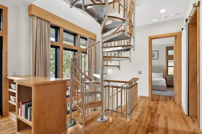 a spiral staircase in a living room with wooden floors at Brighton Cottage in Rosemary Beach