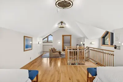 a living room with white walls and wooden floors at Brighton Cottage in Rosemary Beach