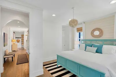 a bedroom with a blue and white bed and a hallway at Flip Flop Dreams in Seacrest