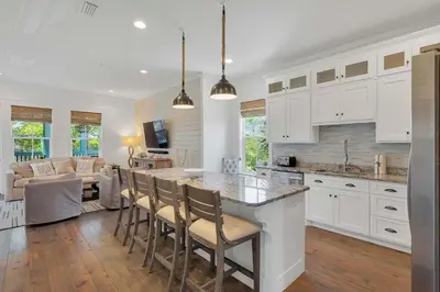 a kitchen with white cabinets and a kitchen island with chairs at Flip Flop Dreams in Seacrest