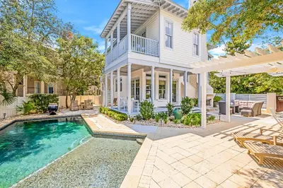 a home with a swimming pool and a house at Butterfly Cottage in Rosemary Beach