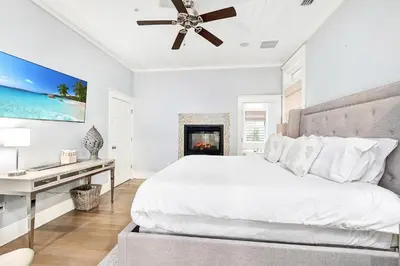a white bedroom with a bed and a fireplace at Butterfly Cottage in Rosemary Beach