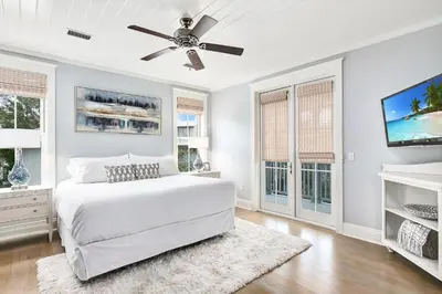 a white bedroom with a bed and a ceiling fan at Butterfly Cottage in Rosemary Beach