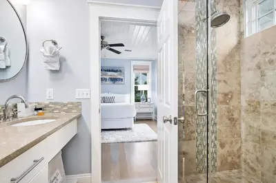 a white bathroom with a shower and a sink at Butterfly Cottage in Rosemary Beach