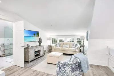 a living room with a couch and a tv at Butterfly Cottage in Rosemary Beach