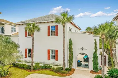 a white house with palm trees in front of it at Clare's Cottage in Seacrest