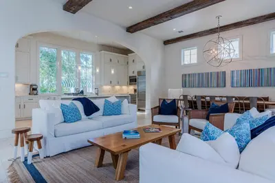 a living room with white couches and a table at Kidd Cottage in Rosemary Beach