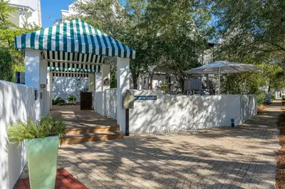 a white fence with a blue and white umbrella at Kidd Cottage in Rosemary Beach