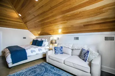 a bedroom with a bed and a white couch at Benoit Cottage in Rosemary Beach