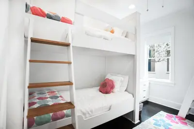 a small bedroom with white bunk beds at Benoit Cottage in Rosemary Beach