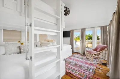 a bedroom with white bunk beds and a chair at Kingston Beach Club in Rosemary Beach