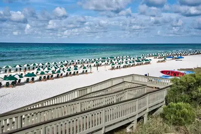 a beach with many umbrellas and chairs and the ocean at Blue Oak in Rosemary Beach