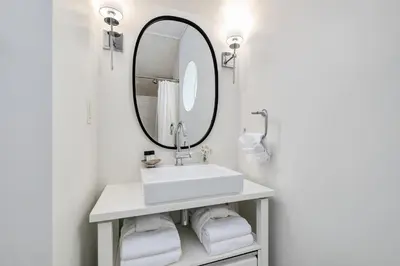 a white bathroom with a sink and a mirror at Blue Oak in Rosemary Beach