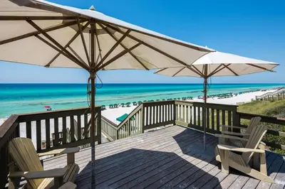a deck with chairs and umbrellas and the beach at Blue Oak in Rosemary Beach