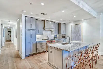 a kitchen with blue cabinets and a kitchen island with bar stools at The Georgetown 403 in Rosemary Beach