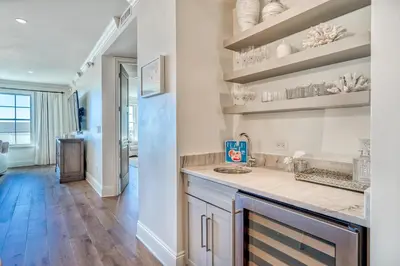 a kitchen with white walls and wooden floors and shelves at The Georgetown 403 in Rosemary Beach