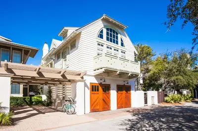 a white house with orange doors on a street at Benoit Carriage House in Rosemary Beach
