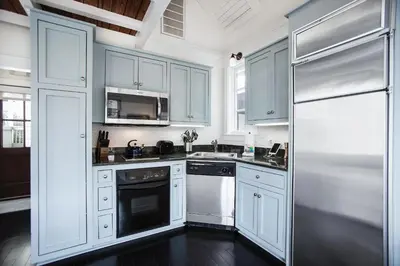 a kitchen with white cabinets and a black dishwasher at Benoit Carriage House in Rosemary Beach