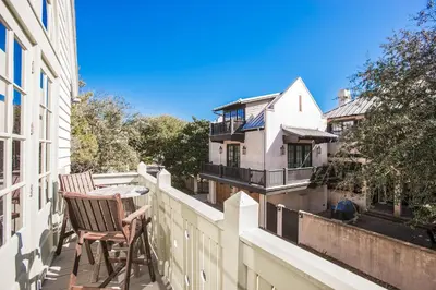 a balcony with two chairs and a table on a building at Benoit Carriage House in Rosemary Beach