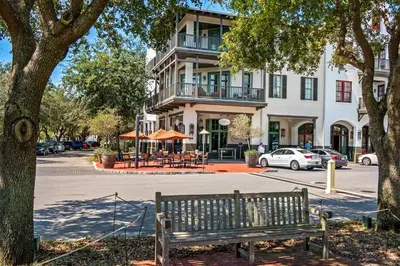 a wooden bench sitting in front of a building at Benoit Carriage House in Rosemary Beach