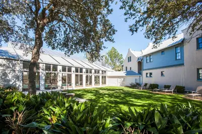 an exterior view of a building with a green yard at Benoit Carriage House in Rosemary Beach