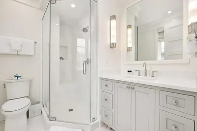 a white bathroom with a shower and a toilet at Bella Carriage House in Rosemary Beach