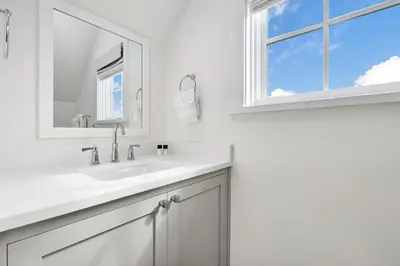 a white bathroom with a sink and a window at Bella Carriage House in Rosemary Beach