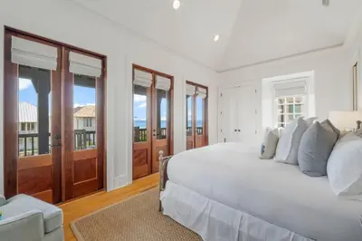 a white bedroom with a large bed and windows at Terra Casa Cottage & Carriage House in Rosemary Beach