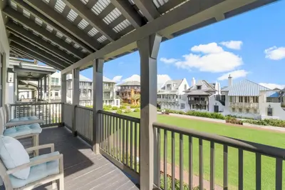 a deck with two chairs and a view of the houses at Terra Casa Cottage & Carriage House in Rosemary Beach