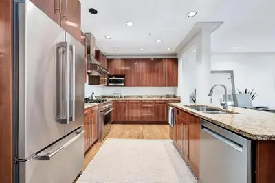 a kitchen with wooden cabinets and a stainless steel refrigerator at Rose at Mercado in Rosemary Beach