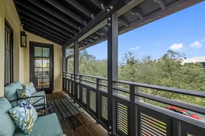 a screened in porch with a couch on a balcony at Rose at Mercado in Rosemary Beach