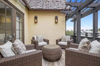 an outdoor patio with wicker chairs and a table at Rose at Mercado in Rosemary Beach