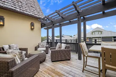a patio with wicker chairs and tables on a deck at Rose at Mercado in Rosemary Beach