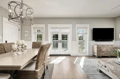 a dining room with a table and chairs and a tv at Just Breathe Flat in Rosemary Beach