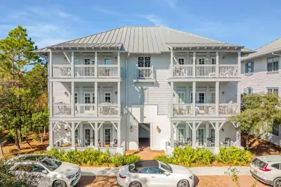 a white house with cars parked in front of it at Just Breathe Flat in Rosemary Beach