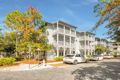 a white building with cars parked in front of it at Just Breathe Flat in Rosemary Beach