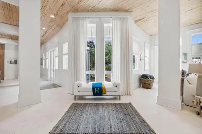 a living room with a white chair and a rug at Moonstruck Cottage and Carriage House in Rosemary Beach