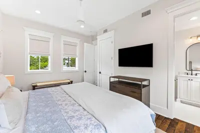 a bedroom with a bed and a flat screen tv at Moonstruck Cottage and Carriage House in Rosemary Beach