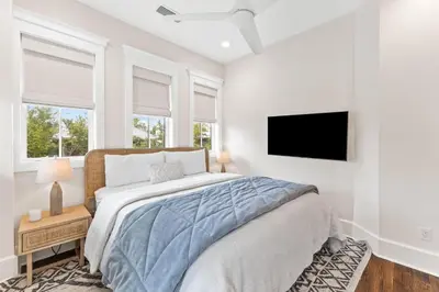 a bedroom with a bed and a flat screen tv at Moonstruck Cottage and Carriage House in Rosemary Beach